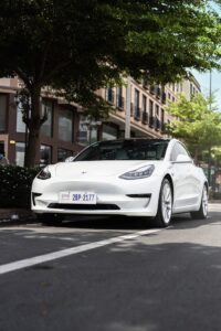 A modern white electric car parked on a sunny street in Phnom Penh, Cambodia.
